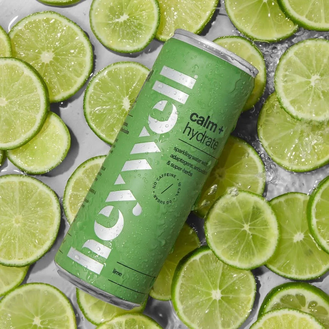 A green Heywell calm and hydrate sparkling can resting on a bed of fresh lime slices
